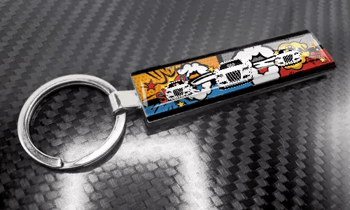 XL slank nøglering i tegneseriestil med et farverigt nummerpladedesign på en kulfibertekstureret overflade
