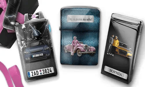 Drei Metallfeuerzeuge mit personalisierten Designs. Das linke Feuerzeug zeigt eine Stadtsilhouette und ein Paar neben einem Auto mit der Aufschrift „BESTE OMA DER WELT“. Das mittlere Feuerzeug stellt ein rosafarbenes Oldtimer-Auto dar, darüber steht „HAB DICH LIEB OMA“. Das rechte Feuerzeug zeigt ein blaues Auto und ein Kennzeichen. Rosafarbene Schleifen verleihen dem Ganzen einen Geschenkcharakter.