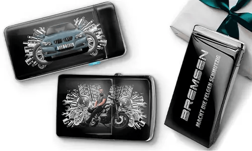 Elegante Geschenkboxen mit einem blauen Auto und einem Biker, umgeben von metallischen Zahnrädern. Eine Box trägt den Text „BREMSEN Macht Die Regeln Schmutzig“, was einen dynamischen, kantigen Ton hinzufügt.