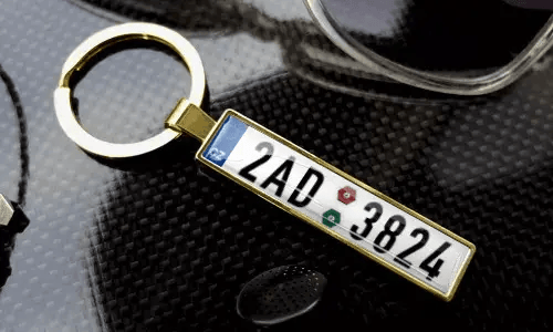 Gold license plate keychain displays engraved text in a polished metal frame