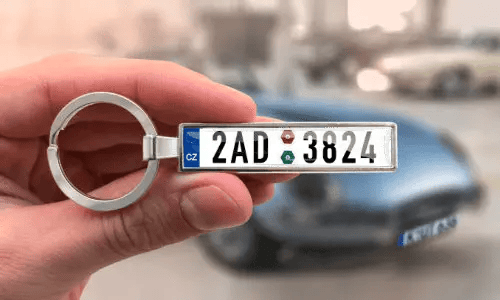Räätälöity rekisterikilpiavaimenperä kädessä, taustalla auto