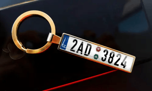 Nummernschild-Schlüsselanhänger an Schlüsseln in der Tasche, mit Auto im Hintergrund