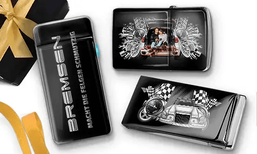 Sleek black lighters with car-themed designs. One features a family in a car; another shows a blue car with checkered flags. Gift box with gold ribbon nearby.