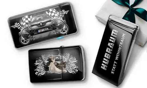 Three black wallets with car-themed designs and checkered flags, set against a white background. One shows a car with wheels, another features a couple, and one has 