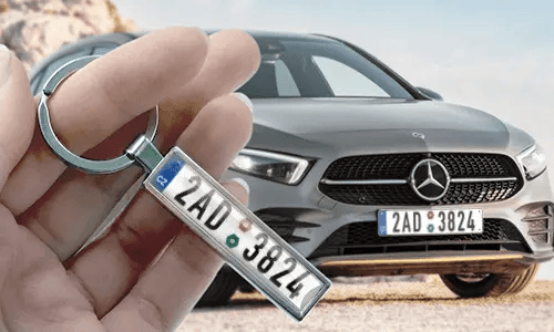 Porte-clés style plaque d’immatriculation comic tenu à la main avec la plaque de voiture correspondante en arrière-plan