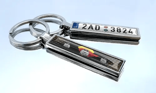 Comic-style license plate keychains with colorful car graphics displayed on a reflective surface