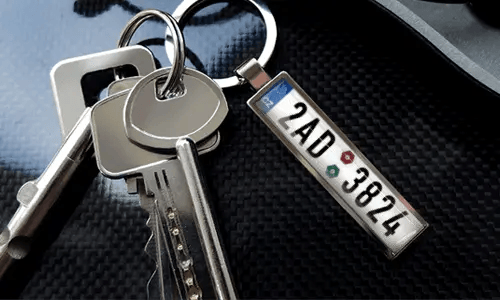 Porte-clés avec pendentif illustrant une voiture et anneau en métal