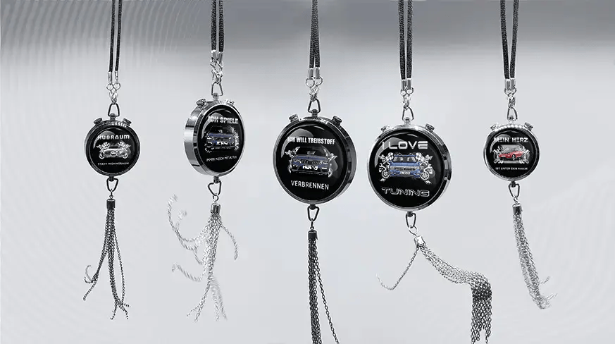 Five round keychains with German car-themed slogans and illustrations, hanging in a row